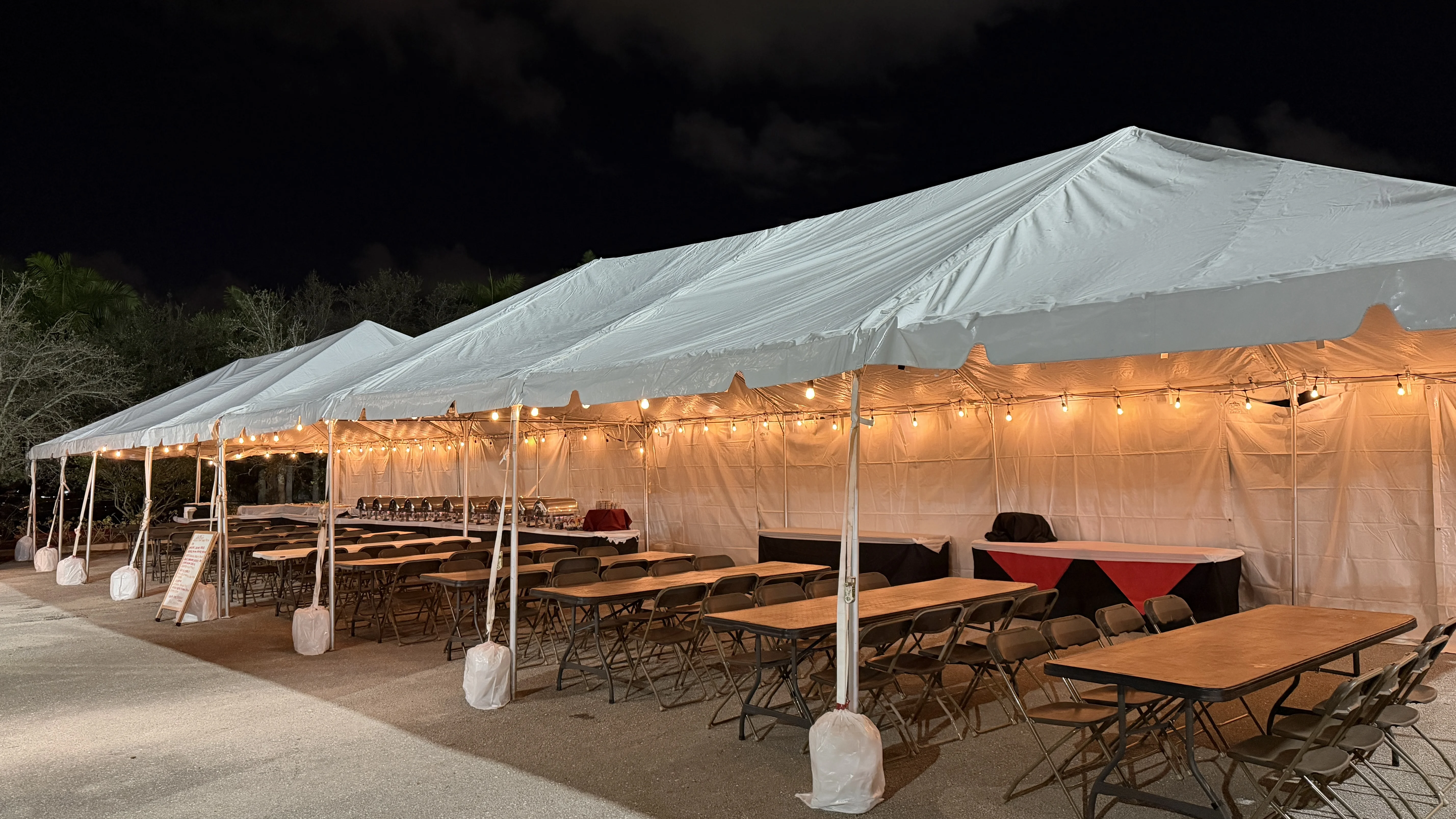 Event tent at night with string lights and banquet setup